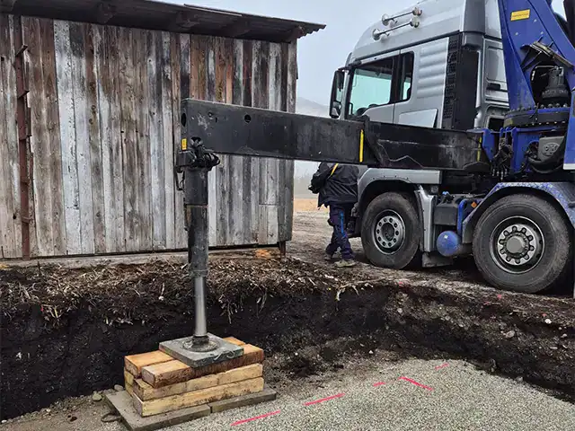 Kranarbeiten: Kran hebt Baumaterialien bei Bauarbeiten an einem Holzhaus.