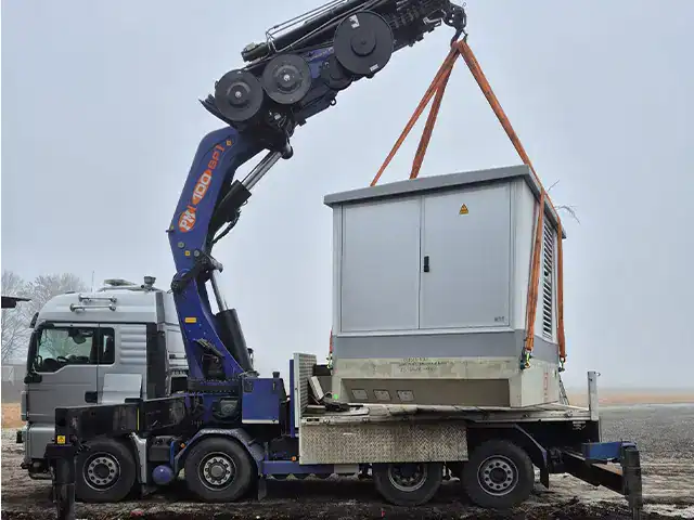 Kran hebt Transformator-Gehäuse auf Baustelle, professionelle Bau- und Kranarbeiten, zuverlässige Kranarbeiten.