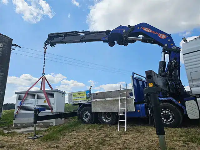 Kranarbeiten: Kran hebt eine große Containerbox auf einen LKW bei Robert Maier GmbH.